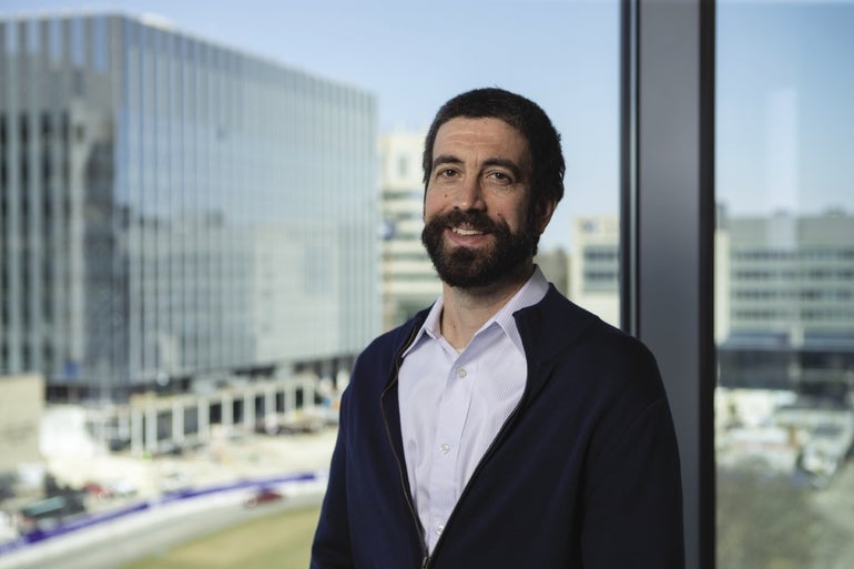 Nate Hafer, who leads the M2D2 incubator at UMass Chan,  stands in front of a window overlooking the UMass Chan Medical School Campus.