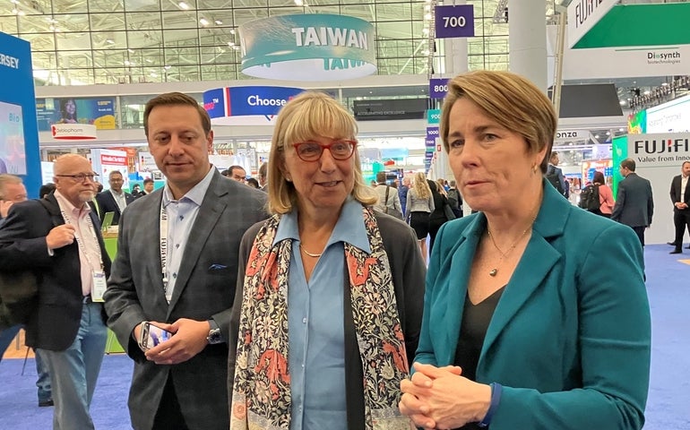 Two women talk while walking around a bioscience trade show