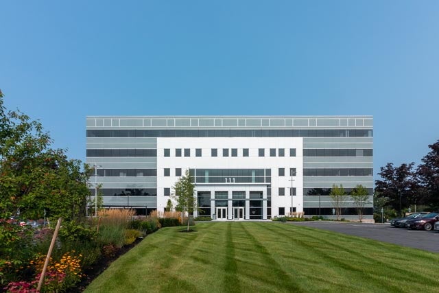 A large modern office building sits behind a lawn