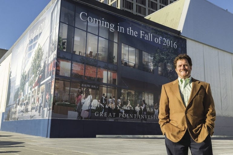 Man stands in suit in front of mural
