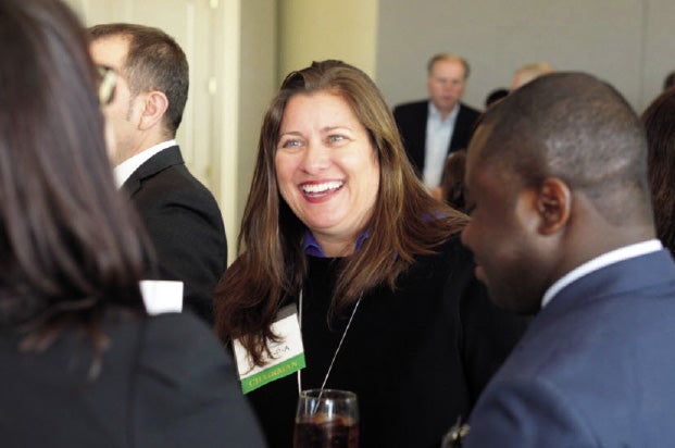 Carla McCall stands in a crowd with a drink in hand as she laughs and talks to someone.