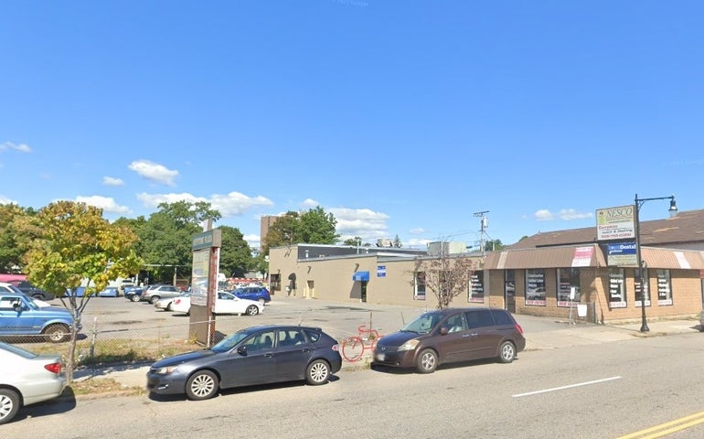 A beige cinderblock building with parking lot