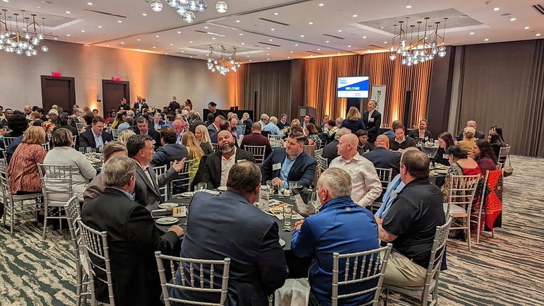 A large group of people sit an banquet tables