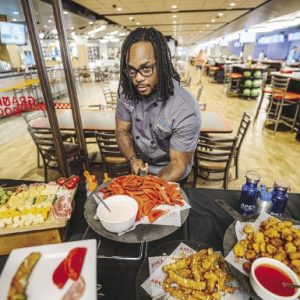 A man hold a platter of food over a buffet table full of food