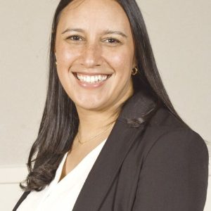 A woman with black hair is wearing a white shirt and black jacket.