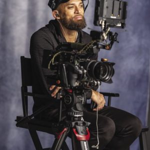 Man in black clothing sits in director's chair