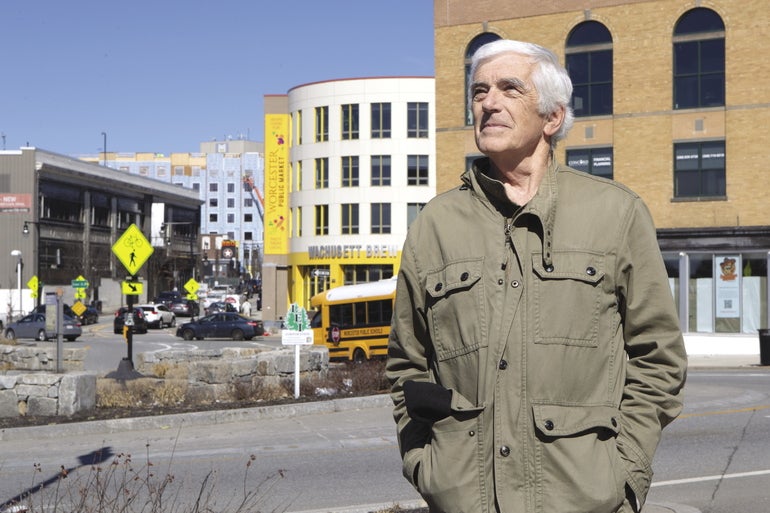 A man stands in front of a traffic circle and large urban buildings