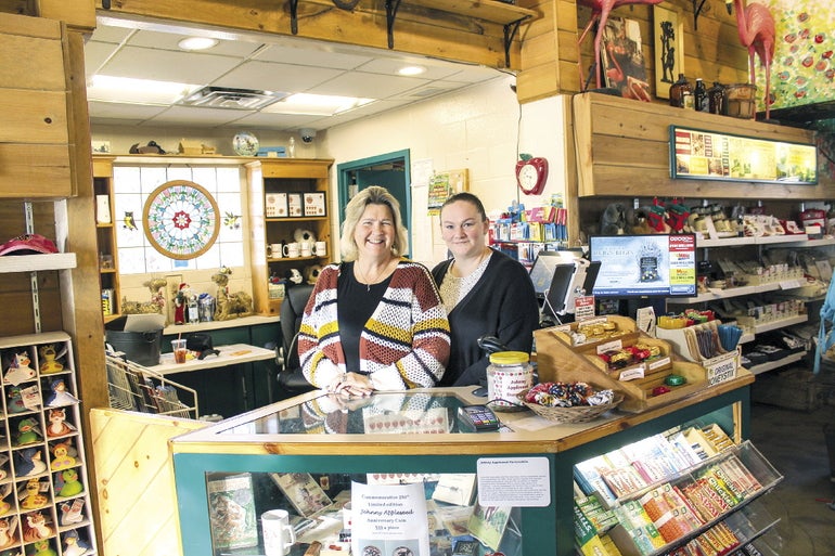 Two woman stand behind a visitor center counter.