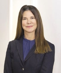 a woman wearing a blouse and jacket smiling