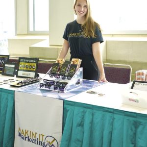 A woman stands in front of a table with a green skirt.