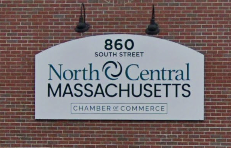 A sign for the North Central Massachusetts Chamber of Commerce on a brick wall.