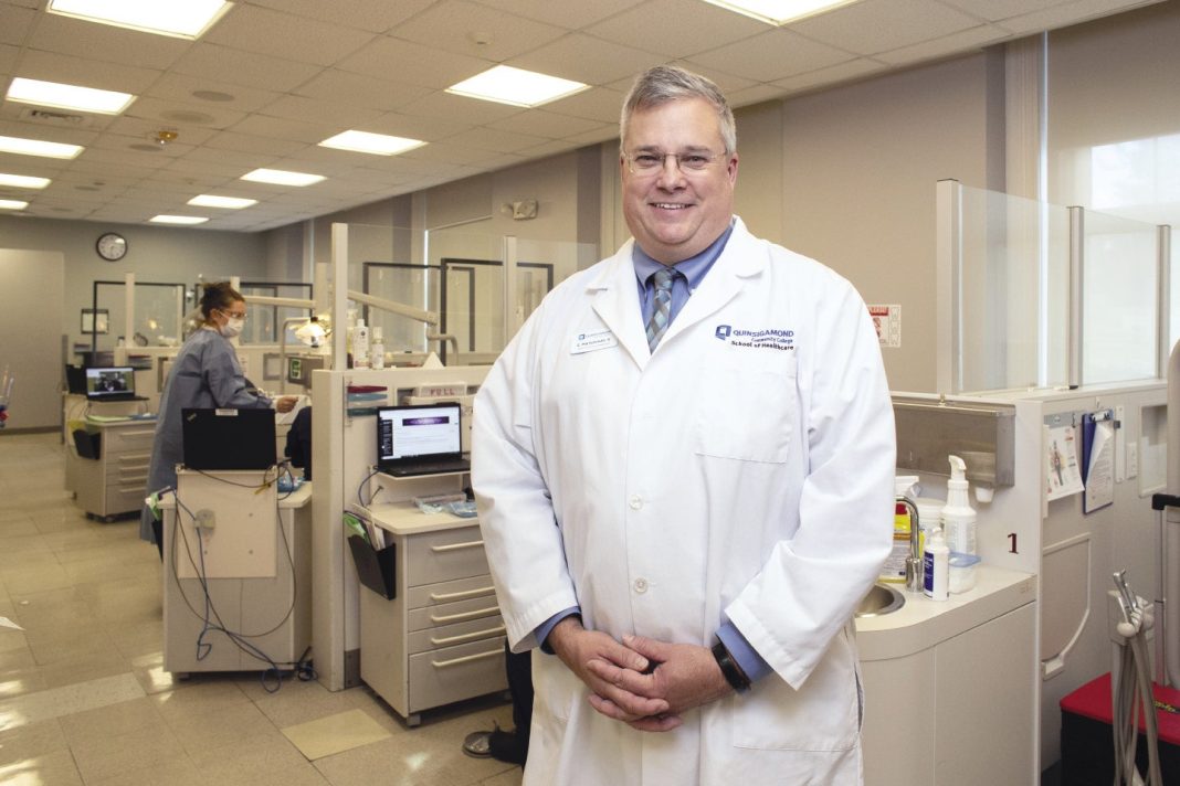A photo of a man wearing a white lab coat