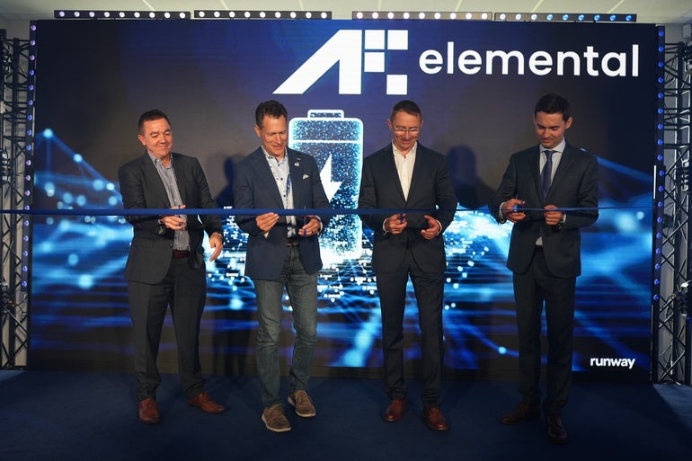 Four men in suits cut a ribbon with scissors