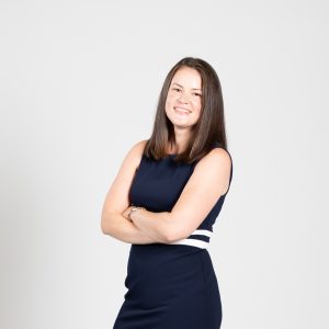 A woman wears a dark blue dress with a white stripe