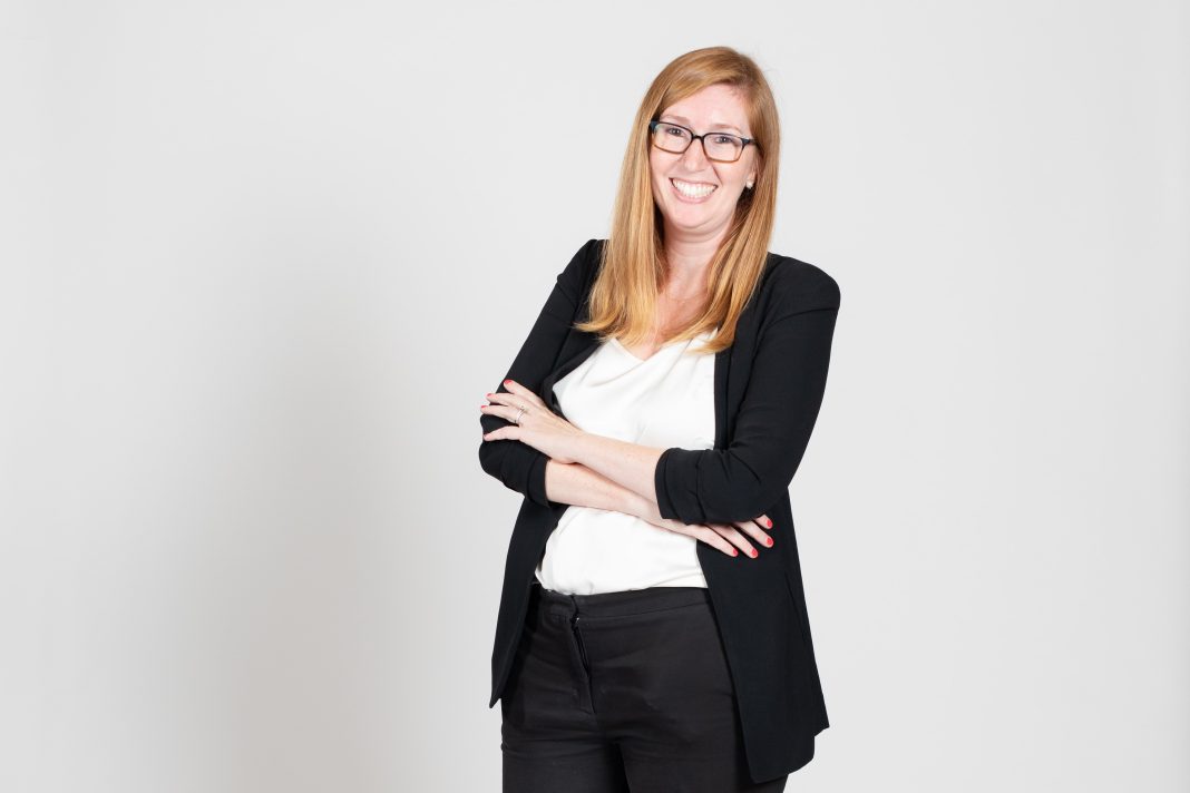 A woman with glasses wears a black jacket.