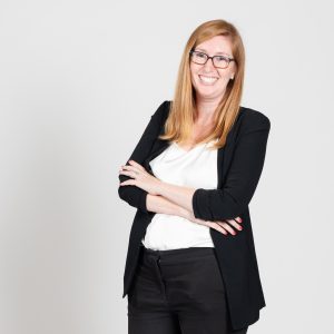 A woman with glasses wears a black jacket.