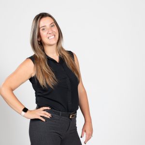A woman wears a black top with gray pants.