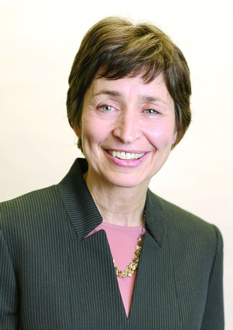 A woman with short brown hair wears a pinstriped top.