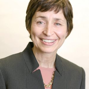 A woman with short brown hair wears a pinstriped top.