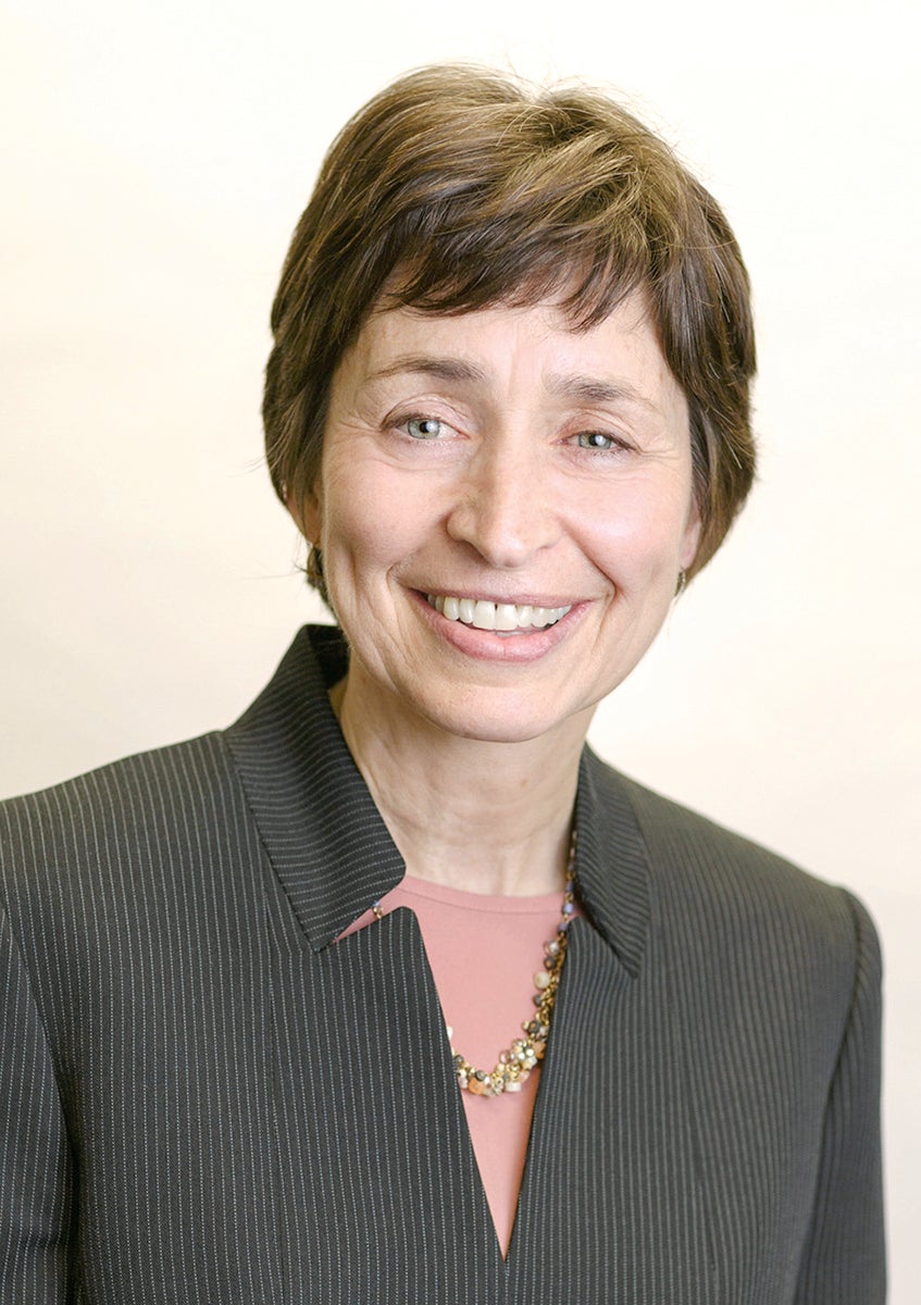 A woman with short brown hair wears a pinstriped top.