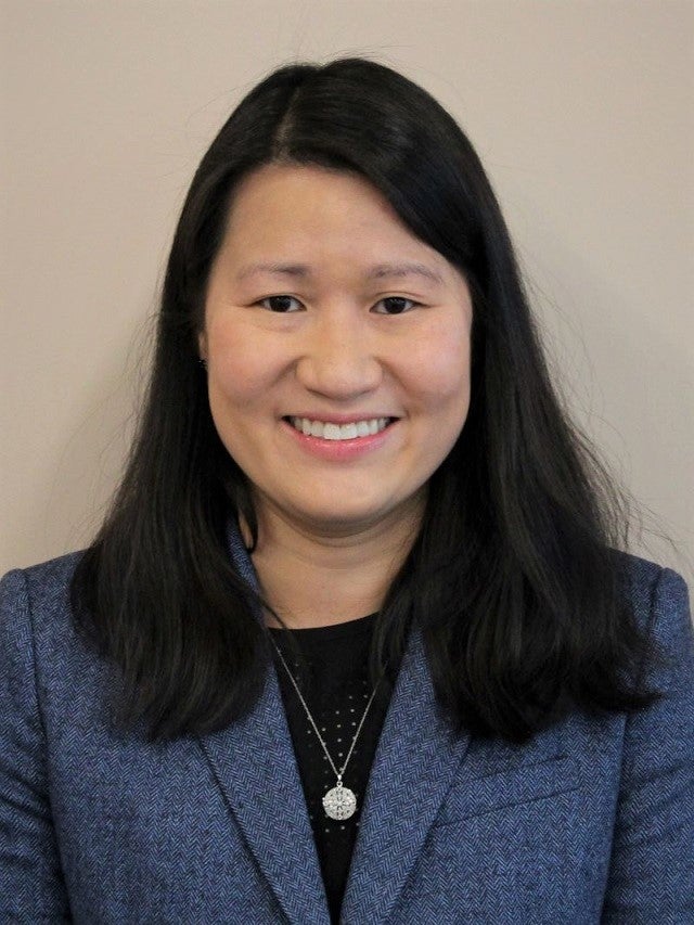 A woman with black hair wears a blue blazer and black top.