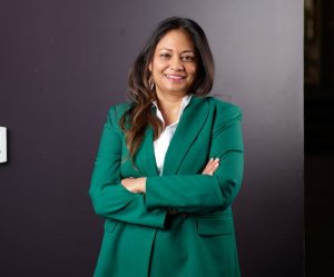 A woman in a green jacket smiles in a portrait photo