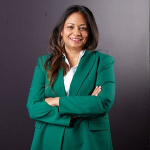 A woman in a green jacket smiles in a portrait photo