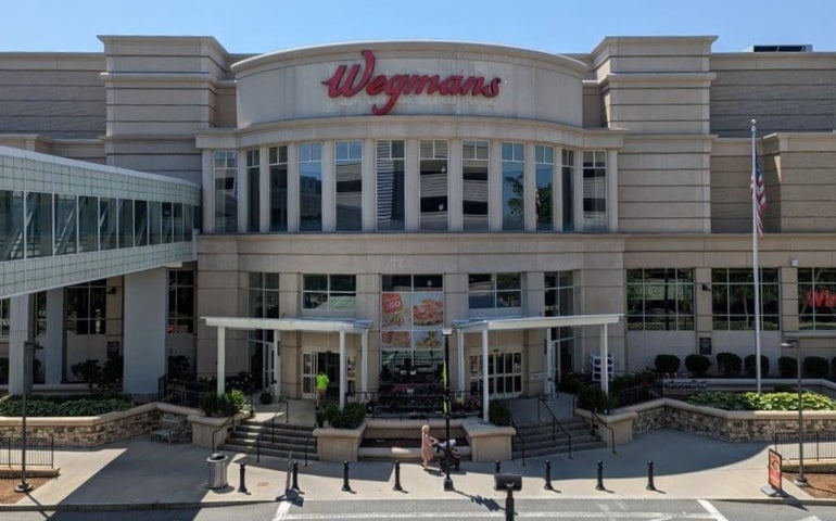 A two-story mall's exterior, showing a retail entrance and a skywalk on the left.