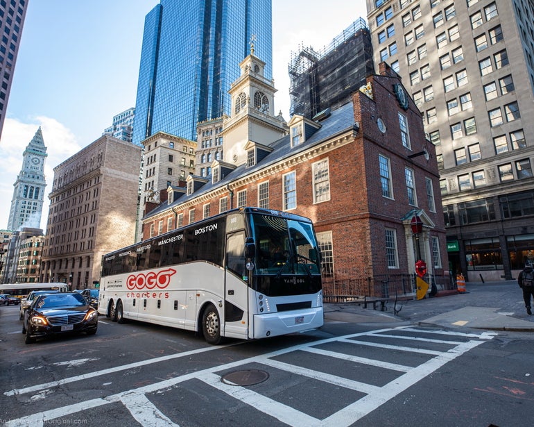 White charter bus parked in front of the Old State House in Boston.