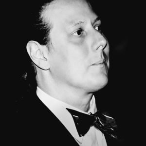 A black-and-white photo of a man in a tux looking to the upper right