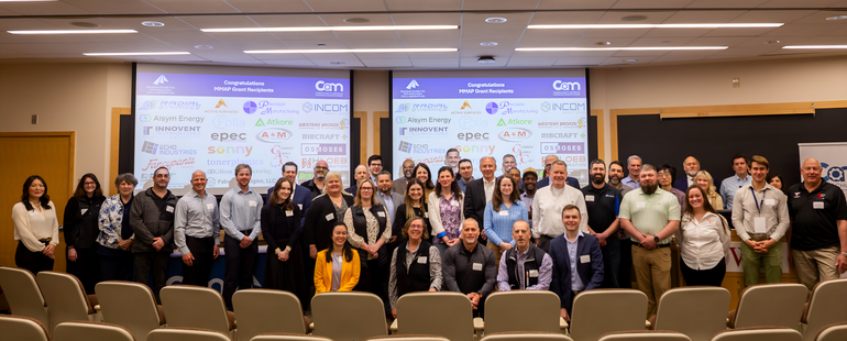 A large group of people pose for a photo in a lecture hall space