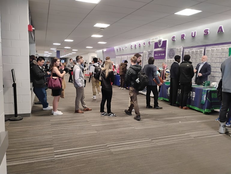 a group of young people stand in line and congregate in a hallway