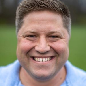A man in a blue shirt smiles