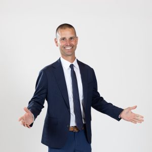 A man wears a blue jacket and blue tie