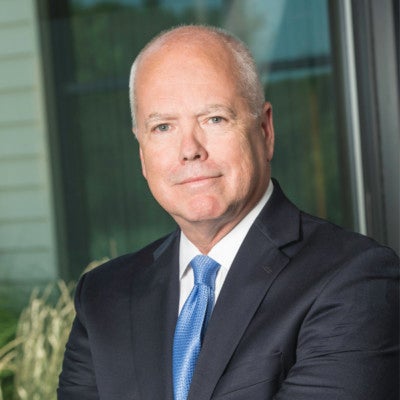 A man with white hair wears a suit.