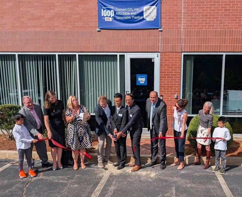 A group of people cut a ribbon in front of a building