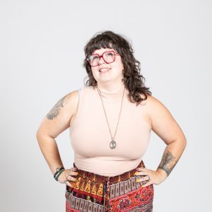 A woman with dark hair wears red glasses.