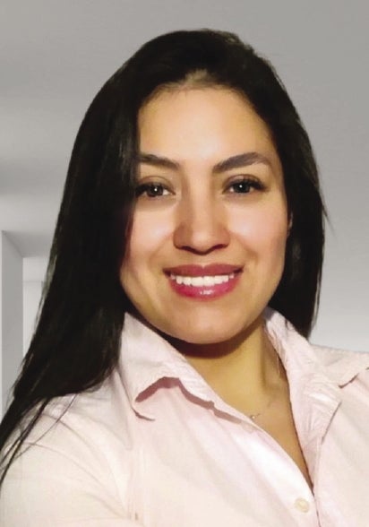 A headshot of a woman with long black hair who is waring a light pink button up.