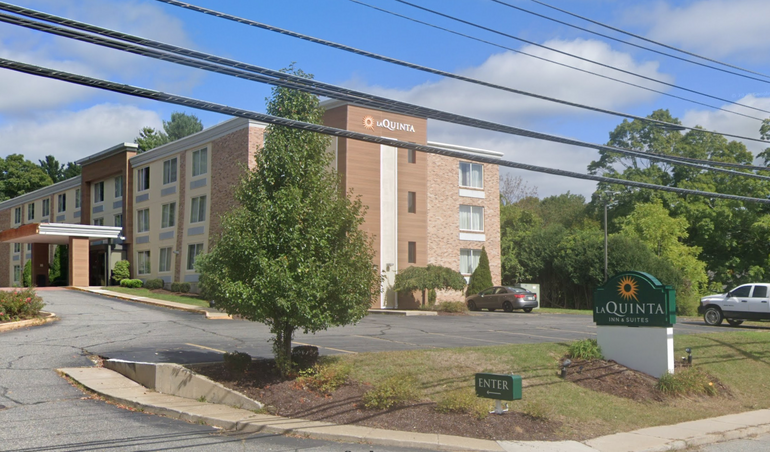 A large building with a tree and a sign in front of it.