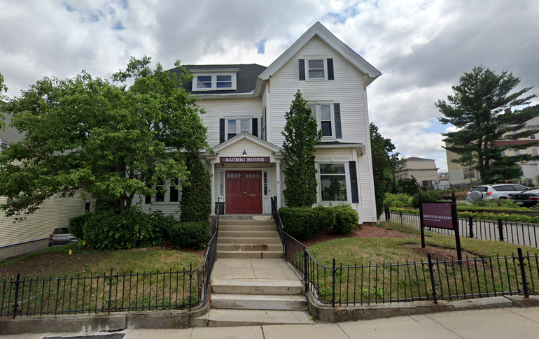 A white three story house with a red sign that says 