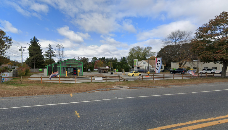 A green structure with glass walls sits in a parking lot