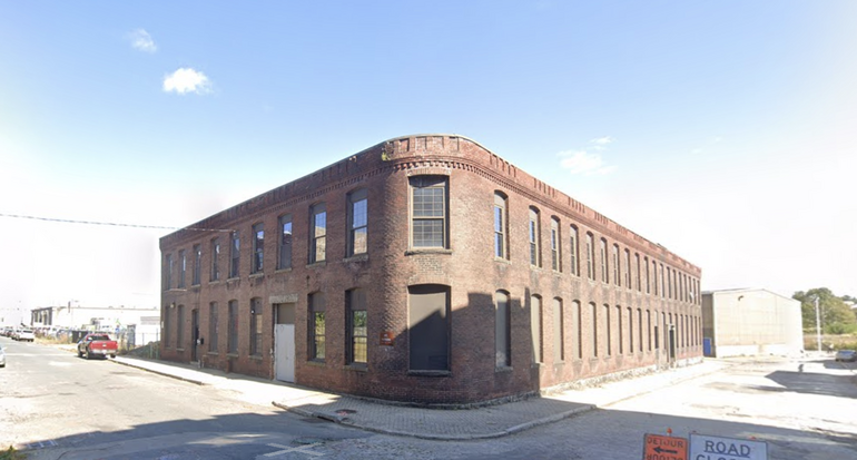 A brick building with a curved side sits on a cross street.
