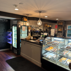 Inside a coffee shop with a refrigerator, a counter, and a baked goods case