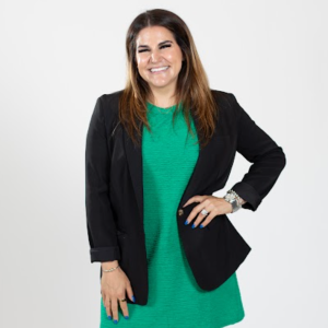 A woman wears a green dress and a black blazer.