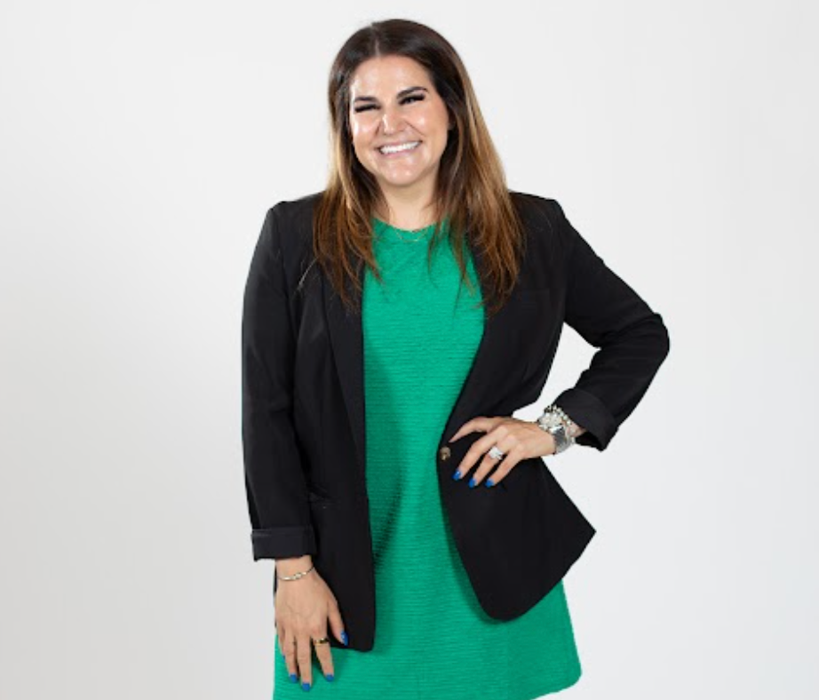 A woman wears a green dress and a black blazer.
