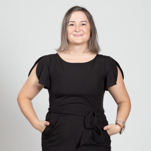 A woman wearing a black jumpsuit stands with her hands in her pockets.