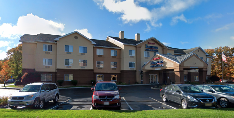 Three-story hotel building behind parking lot