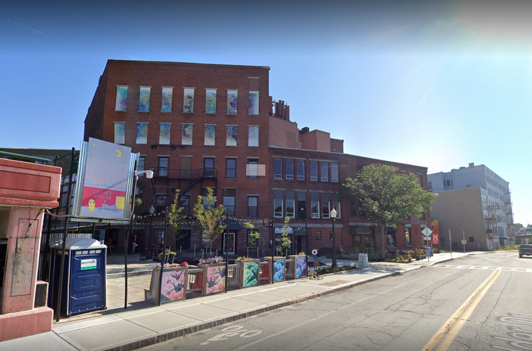 A five story brick building with a courtyard in front.