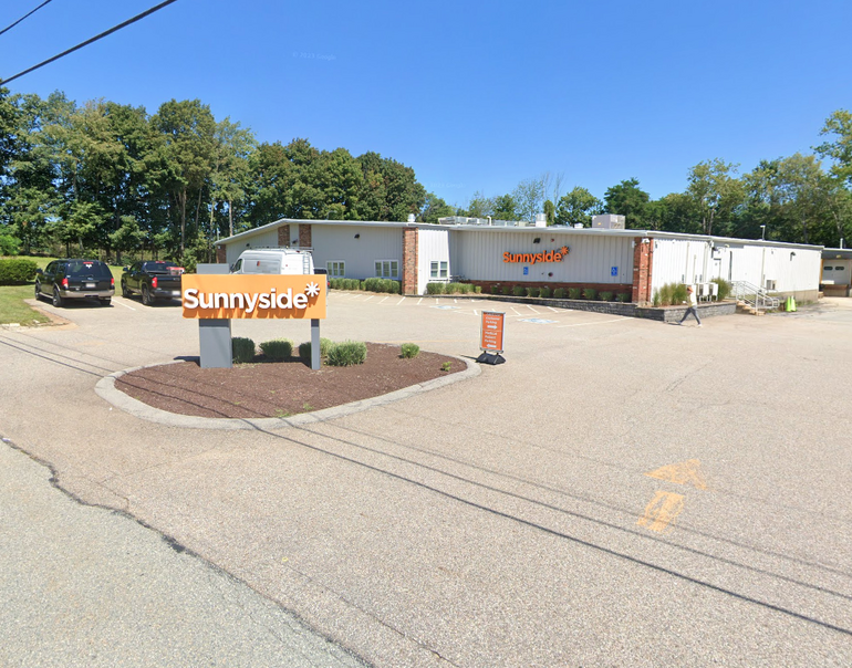 An industrial building with a small parking lot and a sign in front.