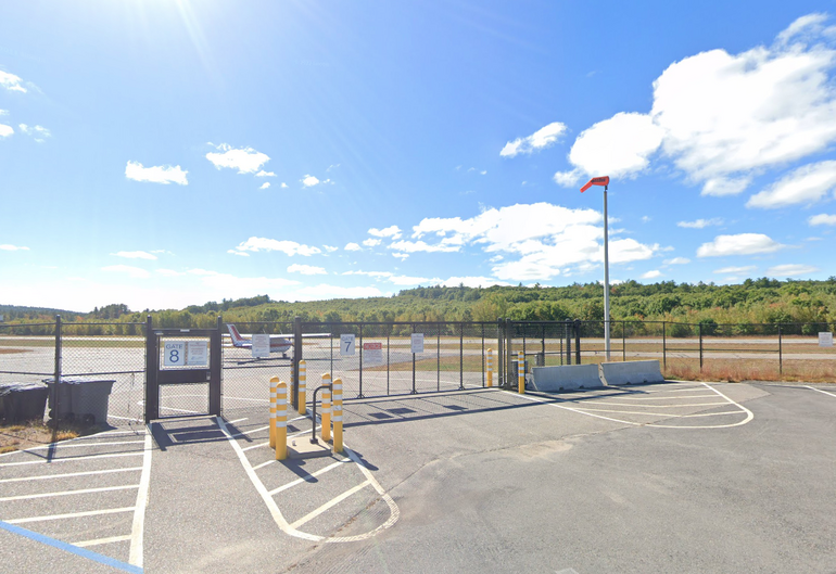 A chainlink fence with a plane parked behind it